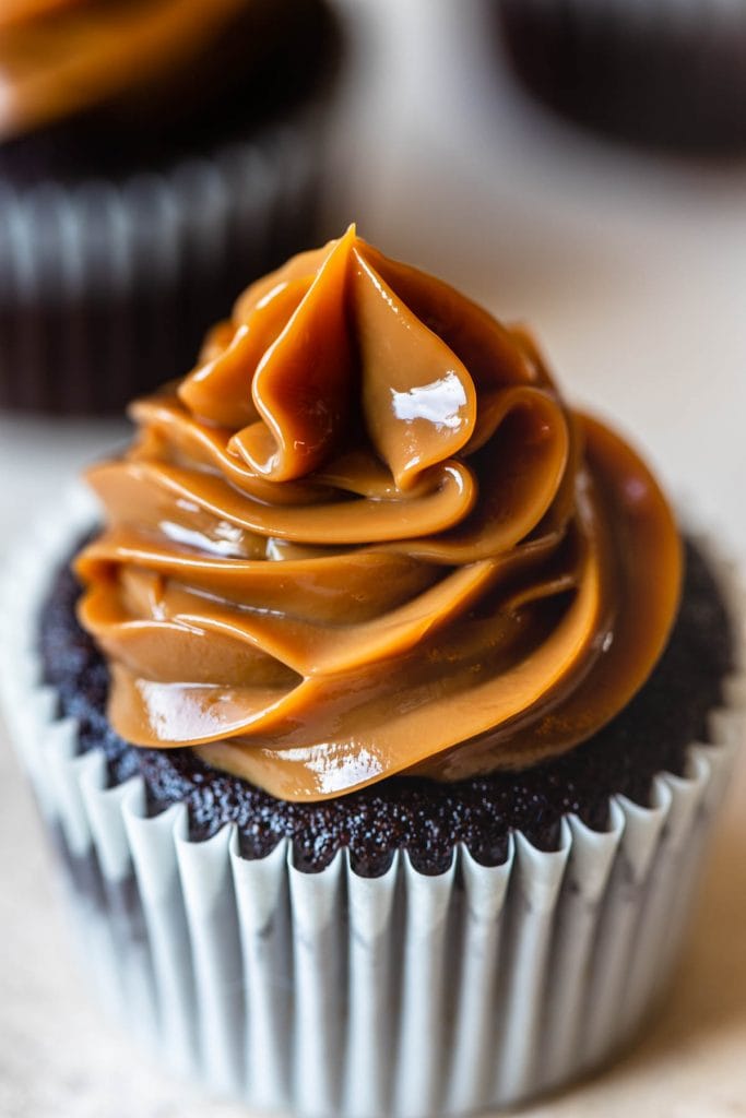 dulce de leche piped on top of a chocolate cupcake