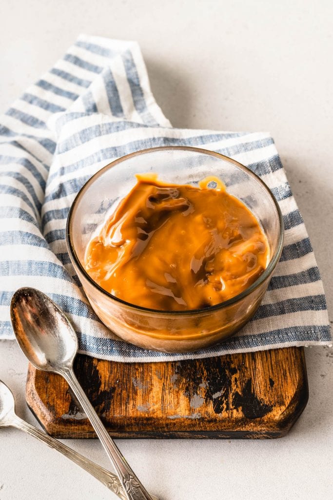 a bowl of dulce de leche with a spoon on the side.
