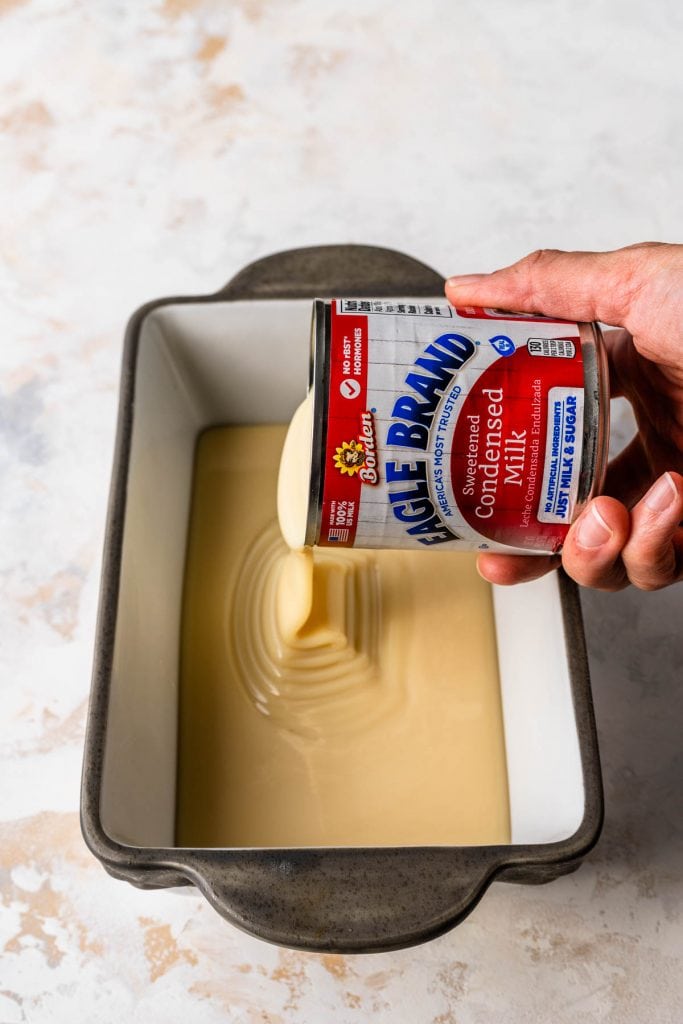 pouring condensed milk in a pan to make oven dulce de leche.