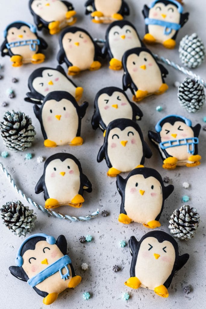 macarons shaped like penguins inside of a cookie box.