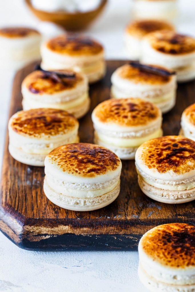 macarons with a bruleed top caramelized, on top of a wooden board.