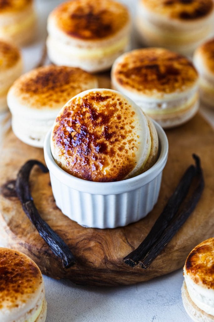 creme brulee macarons in a small ramekin with vanilla beans around.