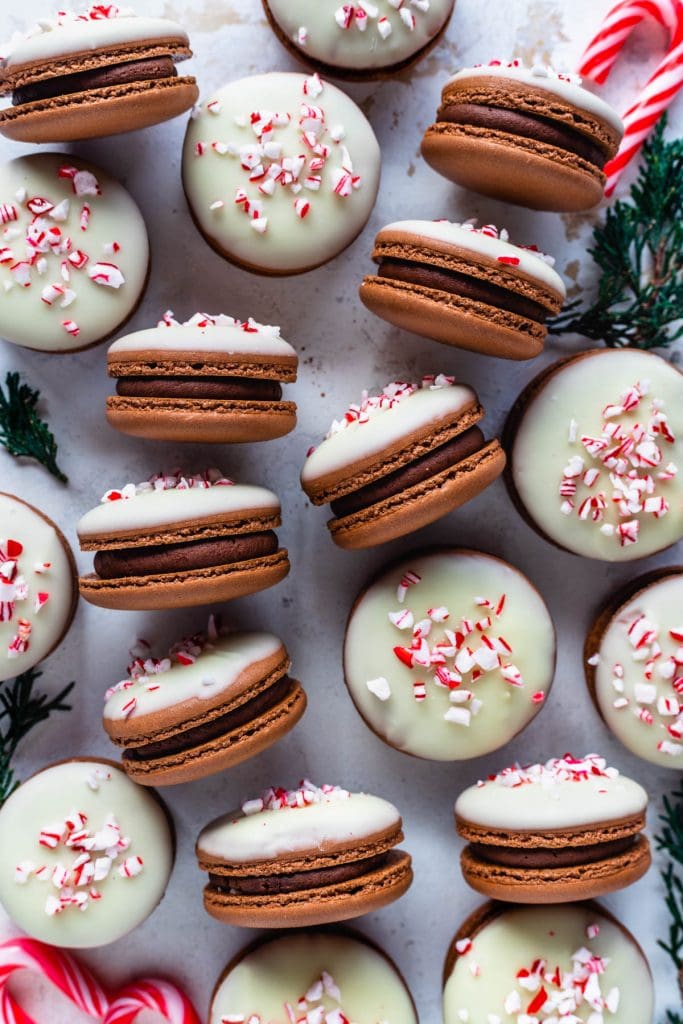 Peppermint Bark Macarons on a plate topped with white chocolate and crushed candy canes.