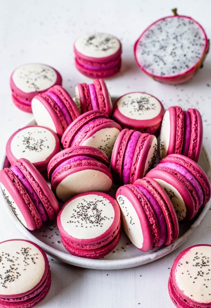 Dragon Fruit Macarons with a bicolor shell, pink and white, and with poppy seeds on top to resemble dragon fruit.