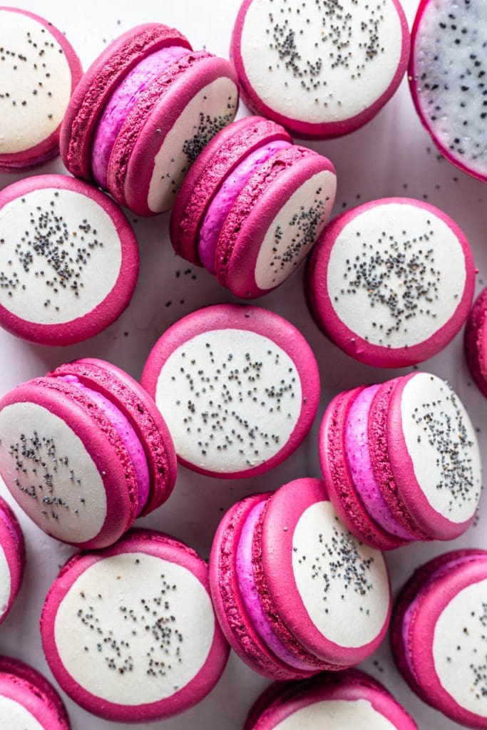 Dragon Fruit Macarons with a bicolor shell, pink and white, and with poppy seeds on top to resemble dragon fruit.