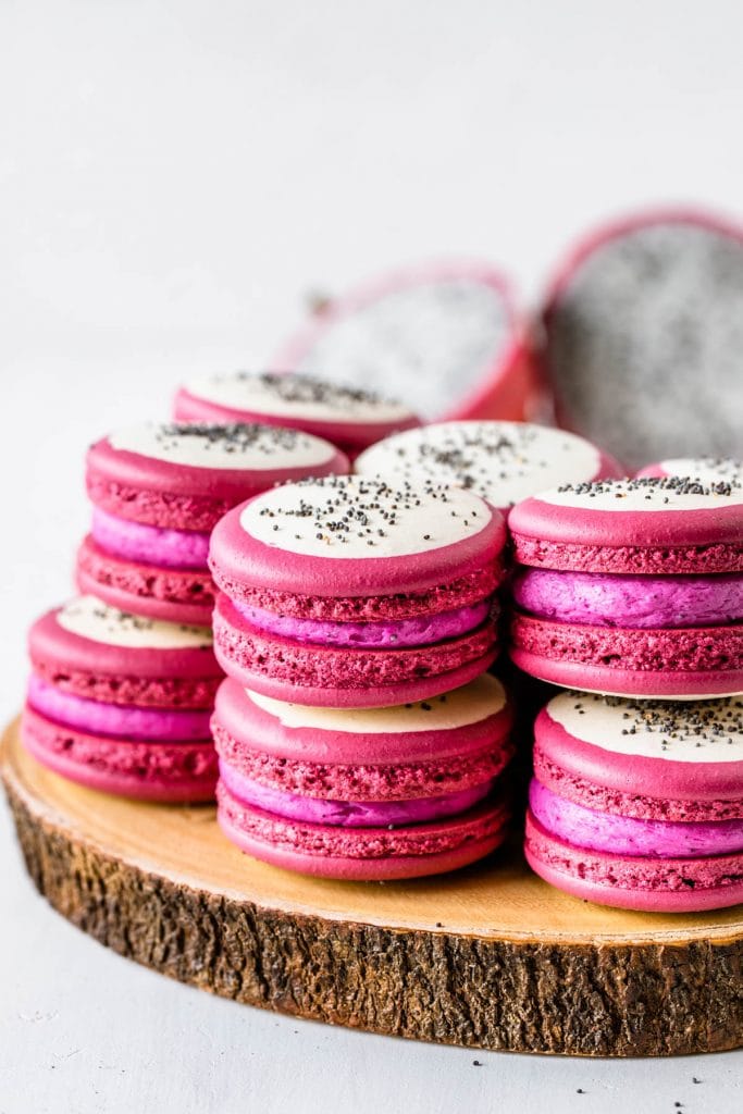 Pitaya macarons with a bicolor shell, pink and white, and with poppy seeds on top to resemble dragon fruit.