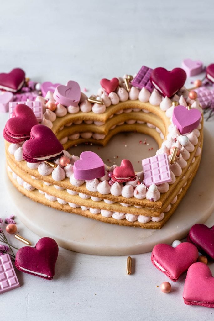 heart cookie cake topped with candy hearts, macarons, and sprinkles.