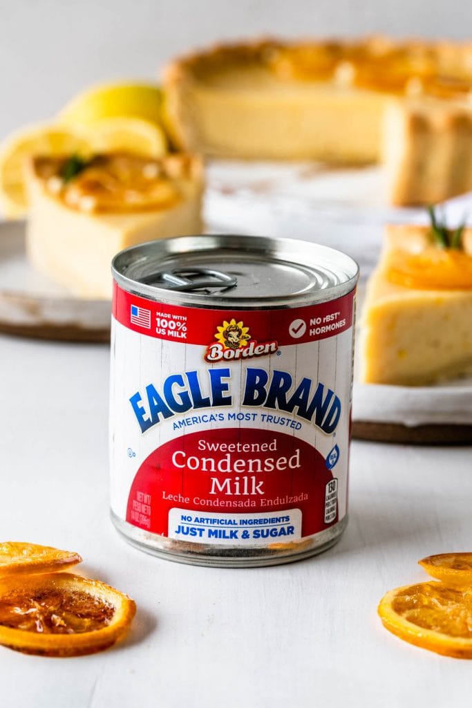 can of eagle brand® sweetened condensed milk with lemon slices on the side and a pie on the background.