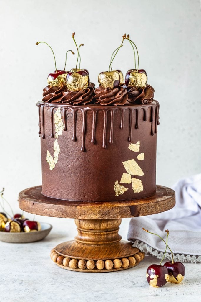Black Forest Cherry Cake topped with chocolate pudding frosting and gold cherries