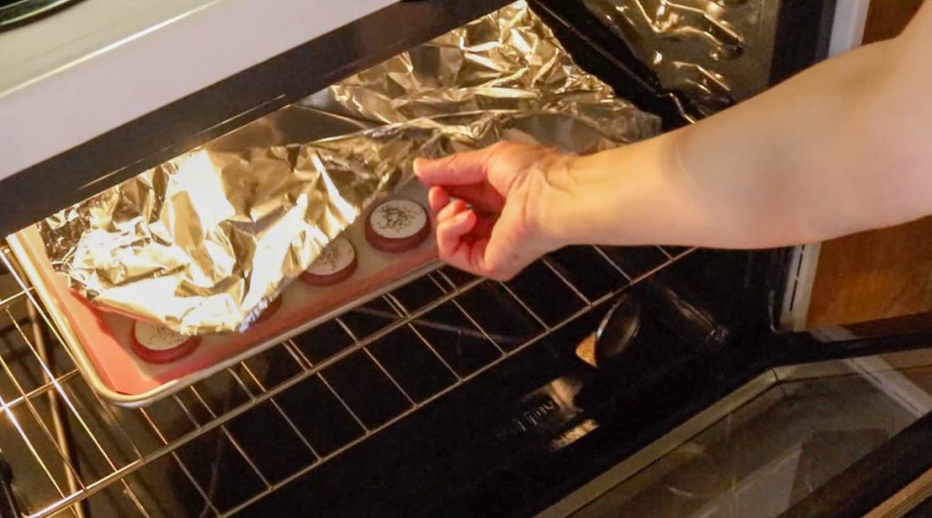 covering a pan of macarons in the oven with foil.