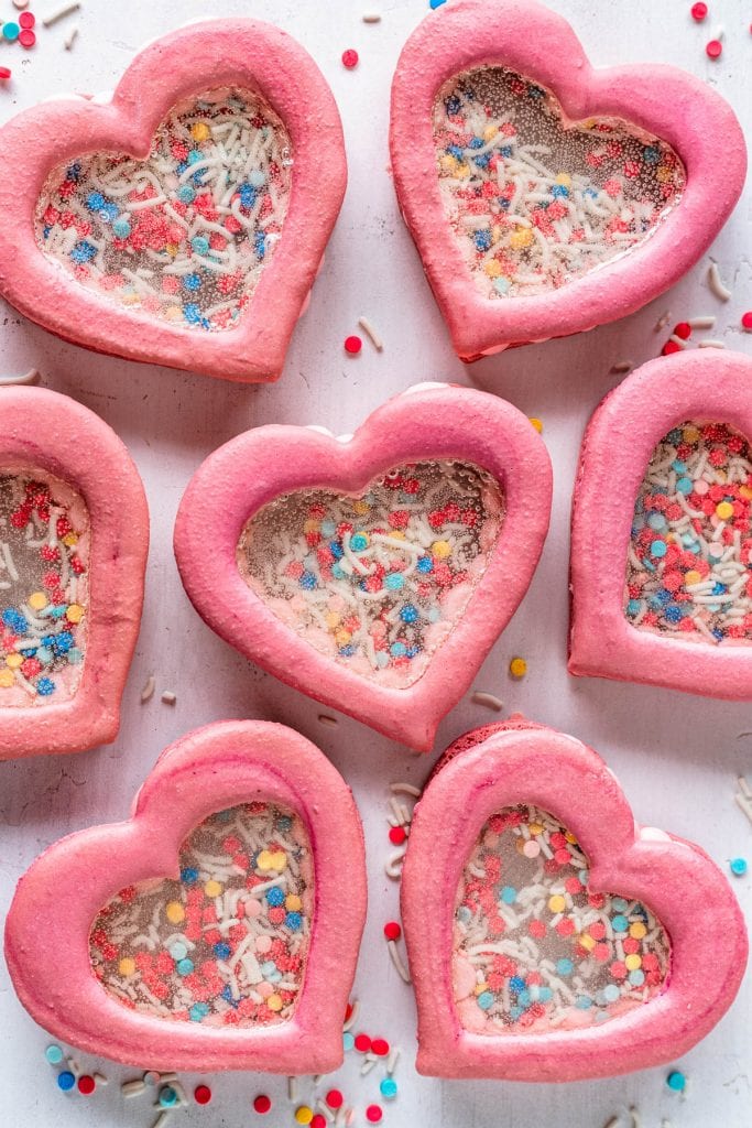 heart shaker macarons filled with sprinkles and they have a transparent middle.