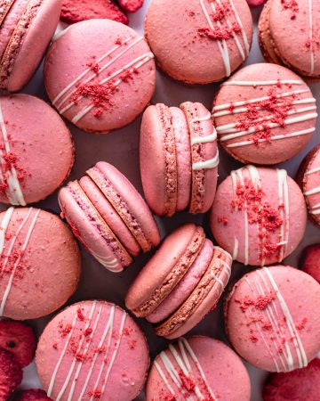 strawberry macarons filled with strawberry buttercream topped with white chocolate drizzle and freeze dried strawberry powder.