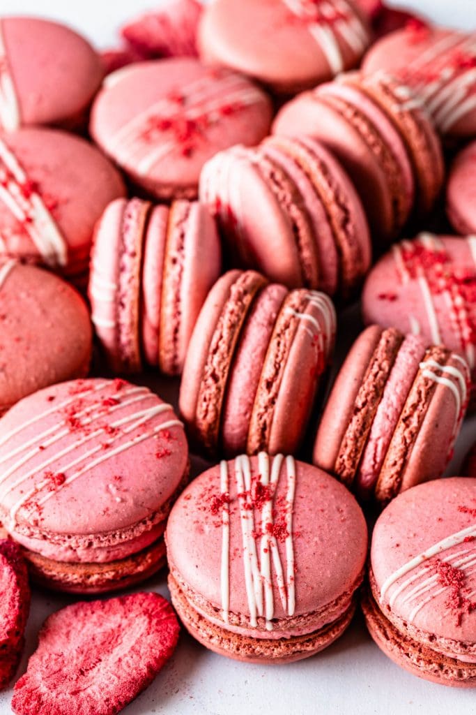 strawberry macarons filled with strawberry buttercream topped with white chocolate drizzle and freeze dried strawberry powder.