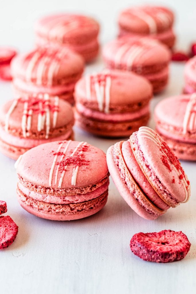 strawberry macarons with a drizzle of chocolate and freeze dried strawberries on top.