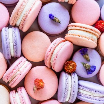purple, pink, and peach color macarons with flowers.