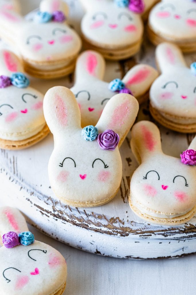 Bunny Macarons with a little chocolate rose in the ear, on a plate with cadbury eggs.