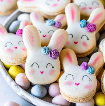 Bunny Macarons with a little chocolate rose in the ear, on a plate with cadbury eggs.