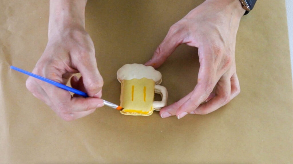 painting a beer macaron with a paint brush.