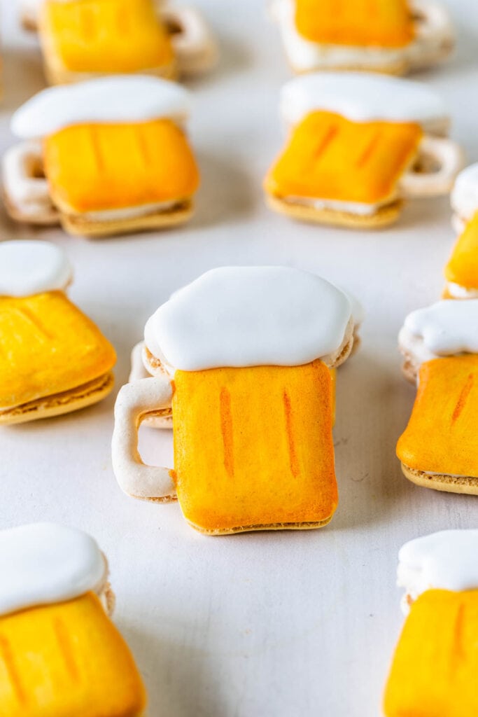 macarons shaped like beer on a wooden board.