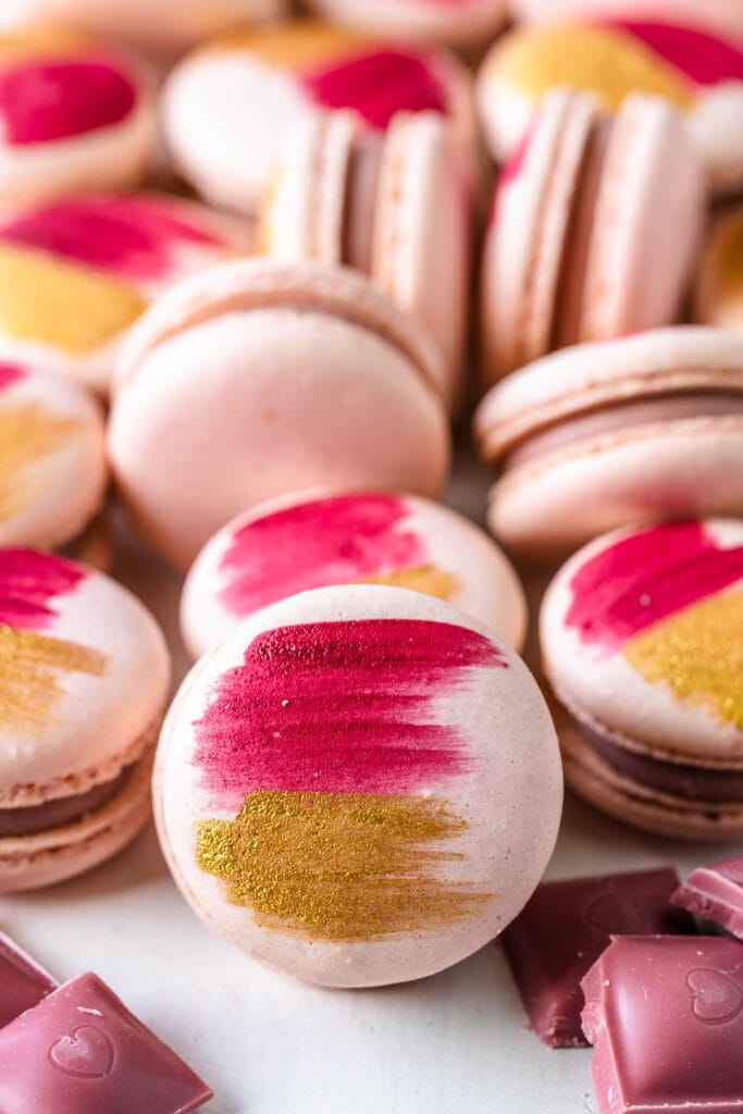 pink macarons with the shells painted with gold and pink, filled with ruby chocolate ganache.