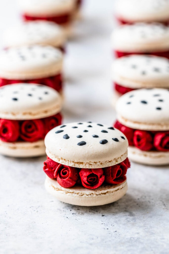 white macarons with black dalmatian spots on them and roses around.