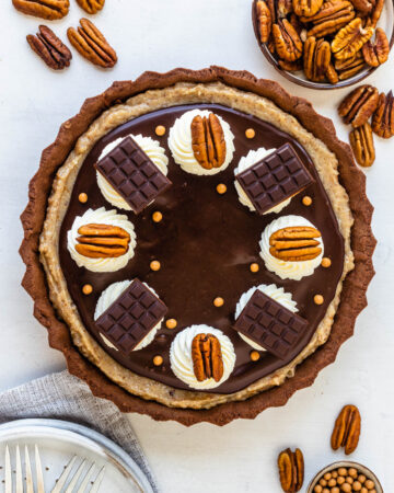 Pecan Fudge Pie topped with pecans and whipped cream and mini chocolate bars.