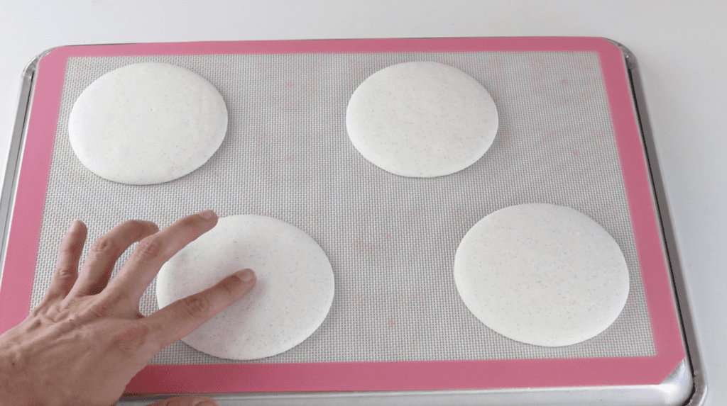 touching the top of a macaron shell to see if it's dry before baking.