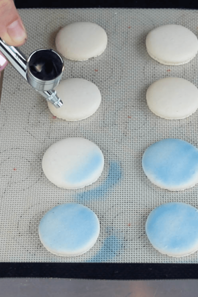 airbrushing macarons with blue food coloring.