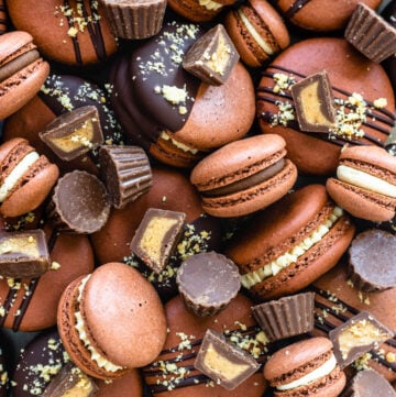 reese's macarons filled with peanut butter ganache and topped with reeses peanut butter cups.