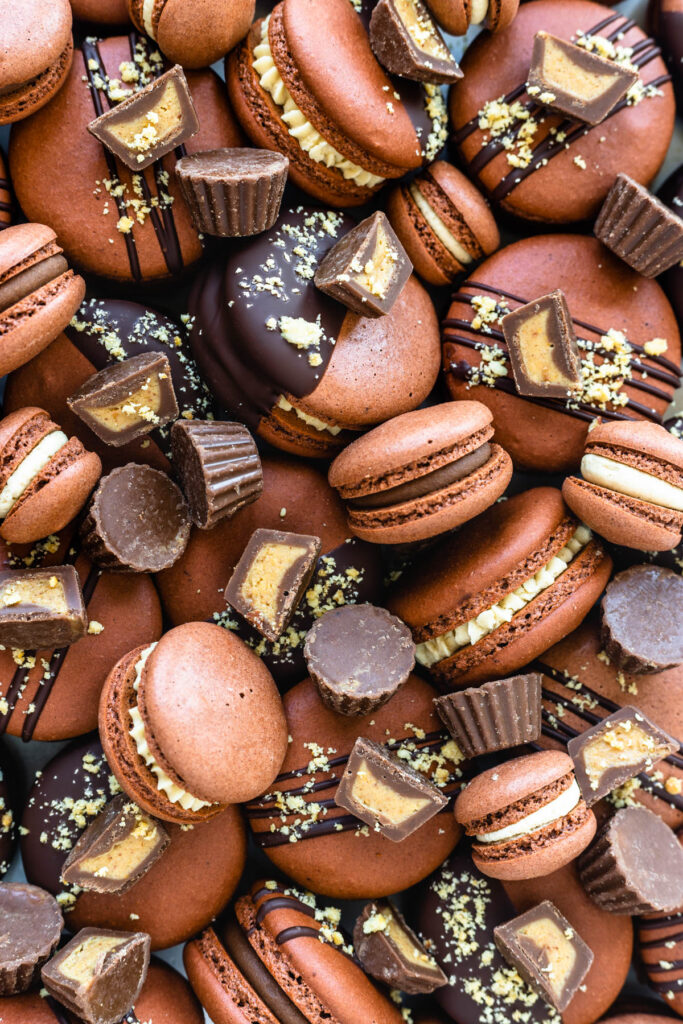 reese's macarons filled with peanut butter ganache and topped with reeses peanut butter cups.