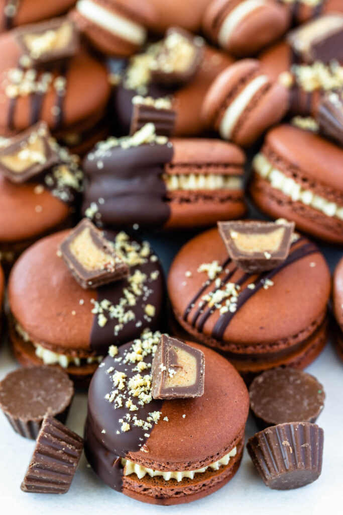 reese's macarons filled with peanut butter ganache and topped with reeses peanut butter cups.