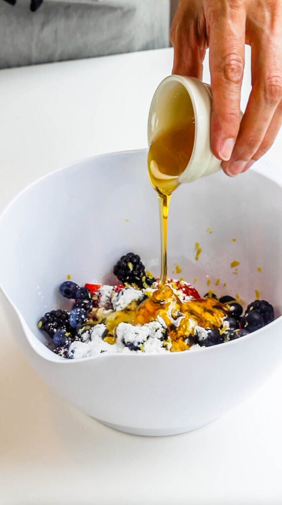 pouring honey over berries to make galette filling.