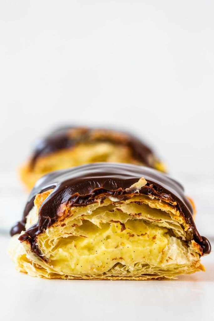 boston cream pastry sliced in half, topped with chocolate.