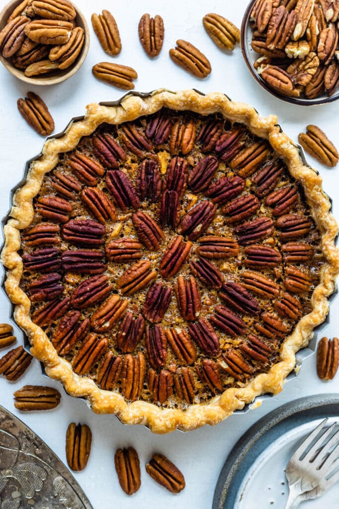 pecan pie flat lay, with pecans scattered around.