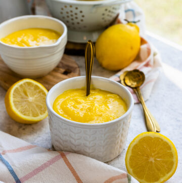 lemon curd in a bowl, with lemons on the background.