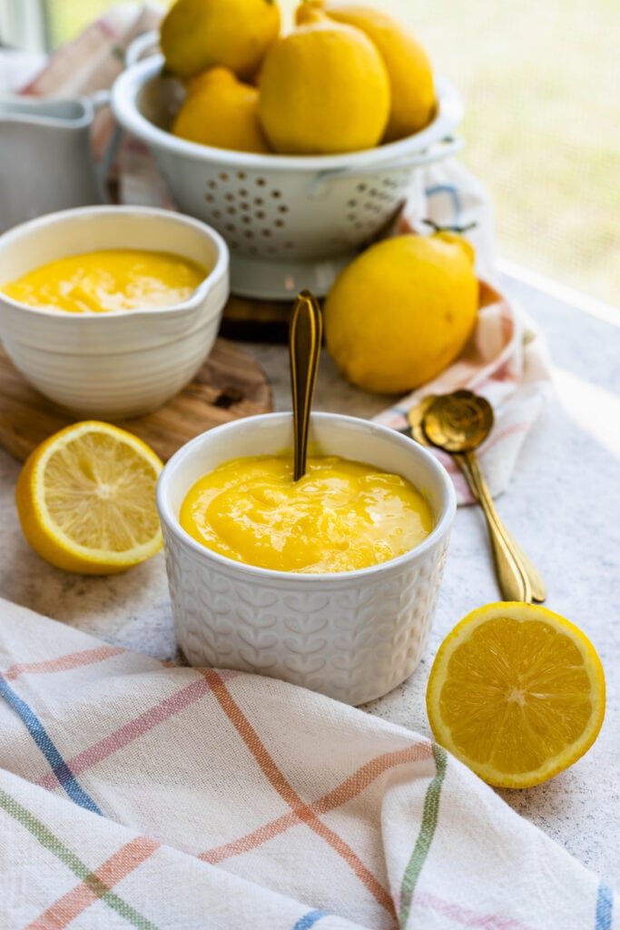 lemon curd in a bowl, with lemons on the background.
