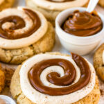 dulce de leche cookies with a swirl of dulce de leche and cream cheese frosting on top.