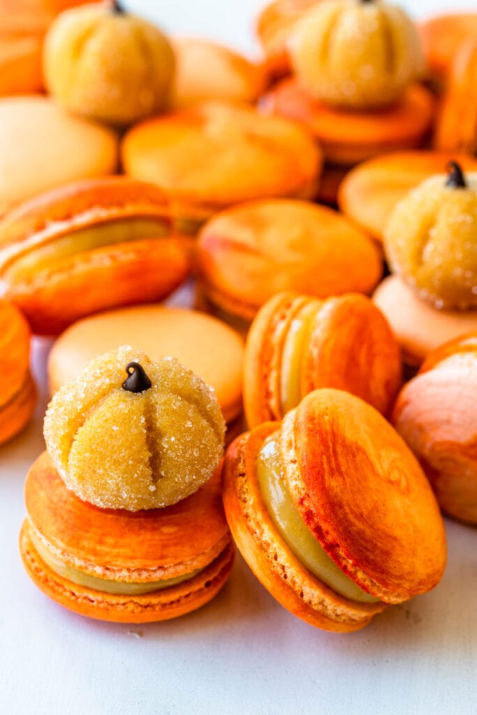 pumpkin brigadeiros on top of orange macarons filled with pumpkin brigadeiro.