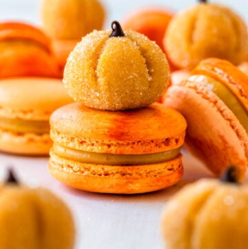 pumpkin brigadeiros on top of orange macarons filled with pumpkin brigadeiro.