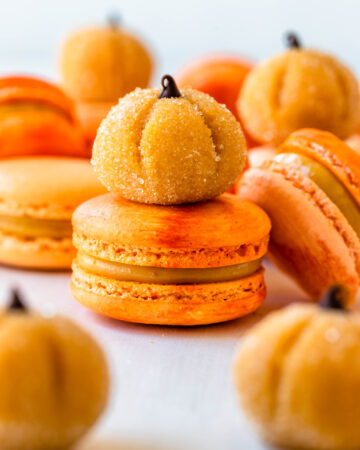 pumpkin brigadeiros on top of orange macarons filled with pumpkin brigadeiro.