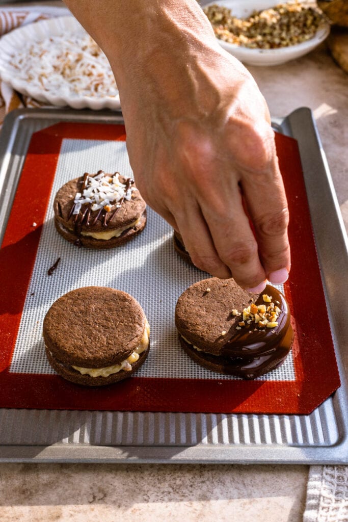 sprinkling chopped pecans on top of cookie dipped in chocolate.