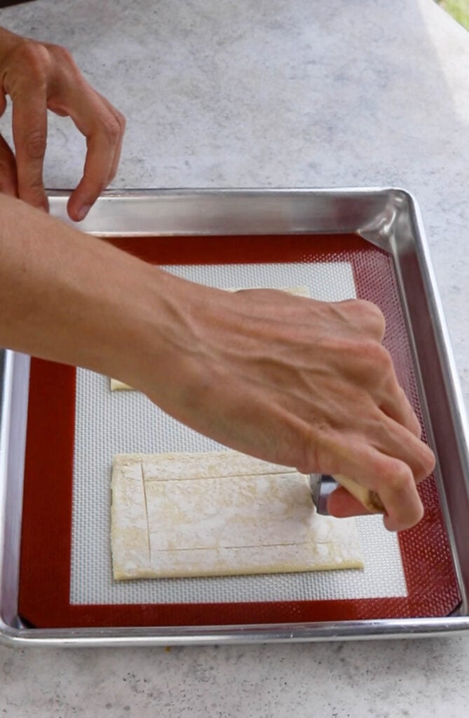 scoring the top of the pastry dough with a knife.
