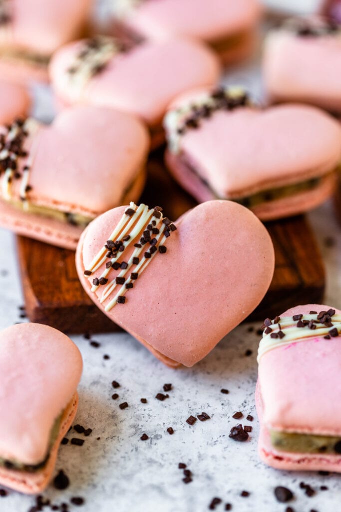 macaron shaped like a heart with a drizzled chocolate decoration on top.