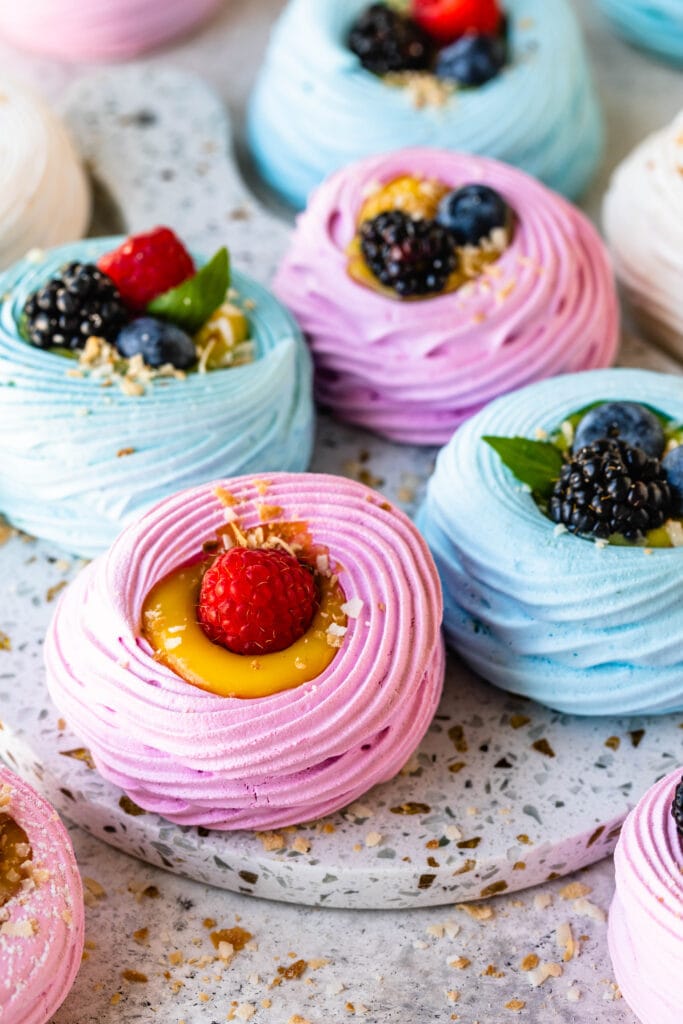 colorful pavlovas filled with lemon curd and topped with berries.