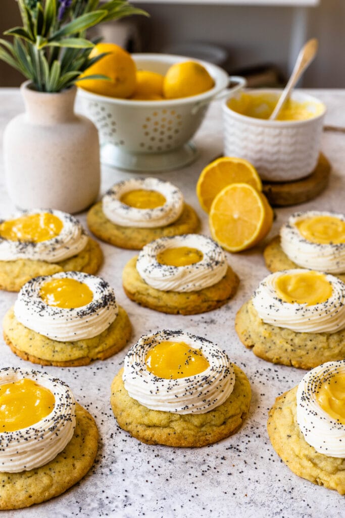Lemon Poppy Seed Cookies on a table with lemons on the back and a flower vase.