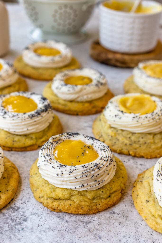 Lemon Poppy Seed Cookies on a table with lemons on the back and a flower vase.