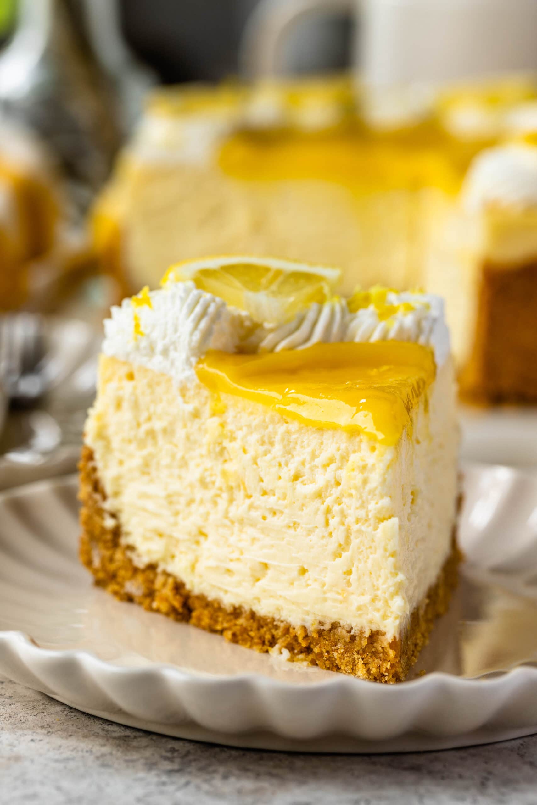 slice of lemon cheesecake topped with lemon curd and whipped cream.