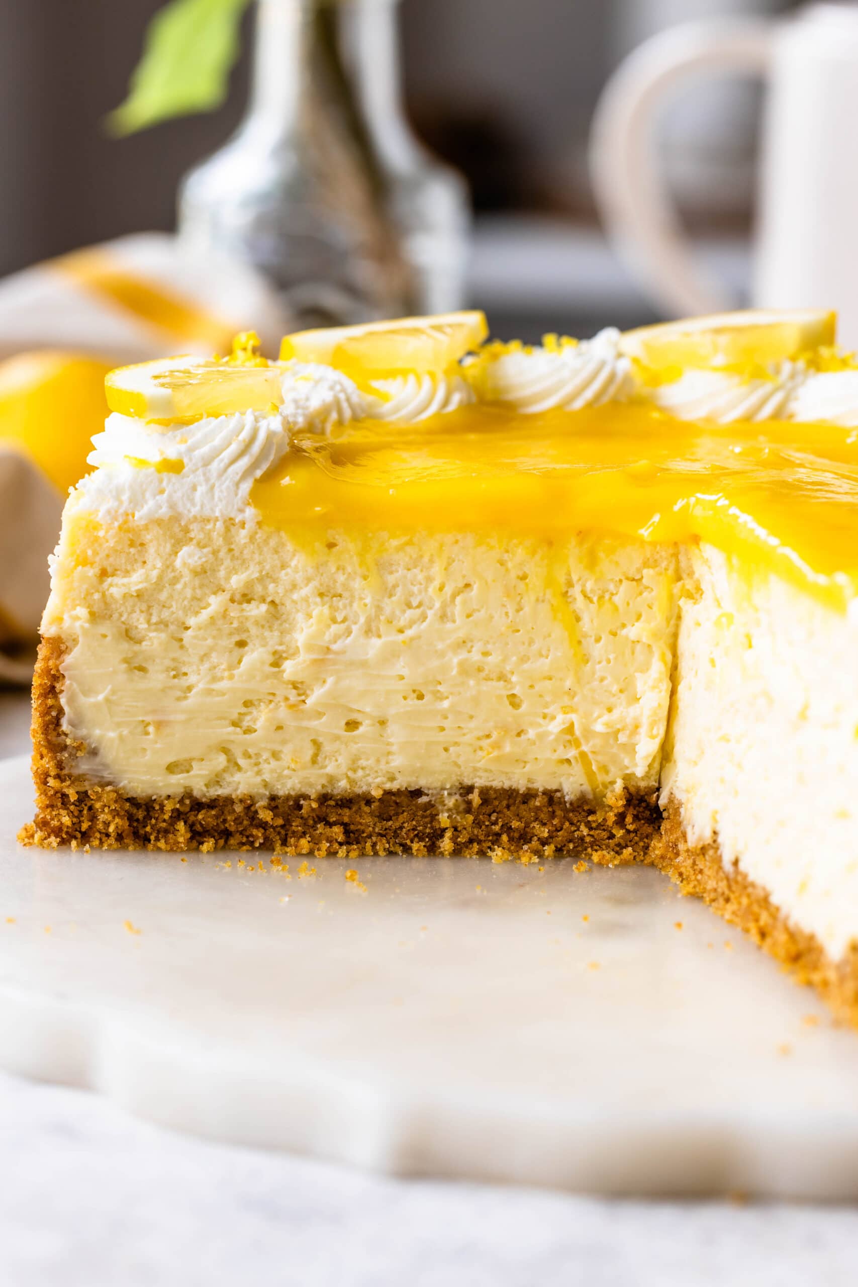 slice of lemon cheesecake topped with lemon curd and whipped cream.