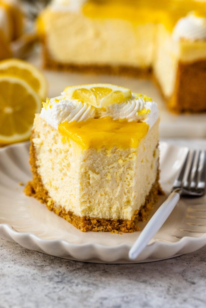 slice of lemon cheesecake topped with lemon curd and whipped cream.