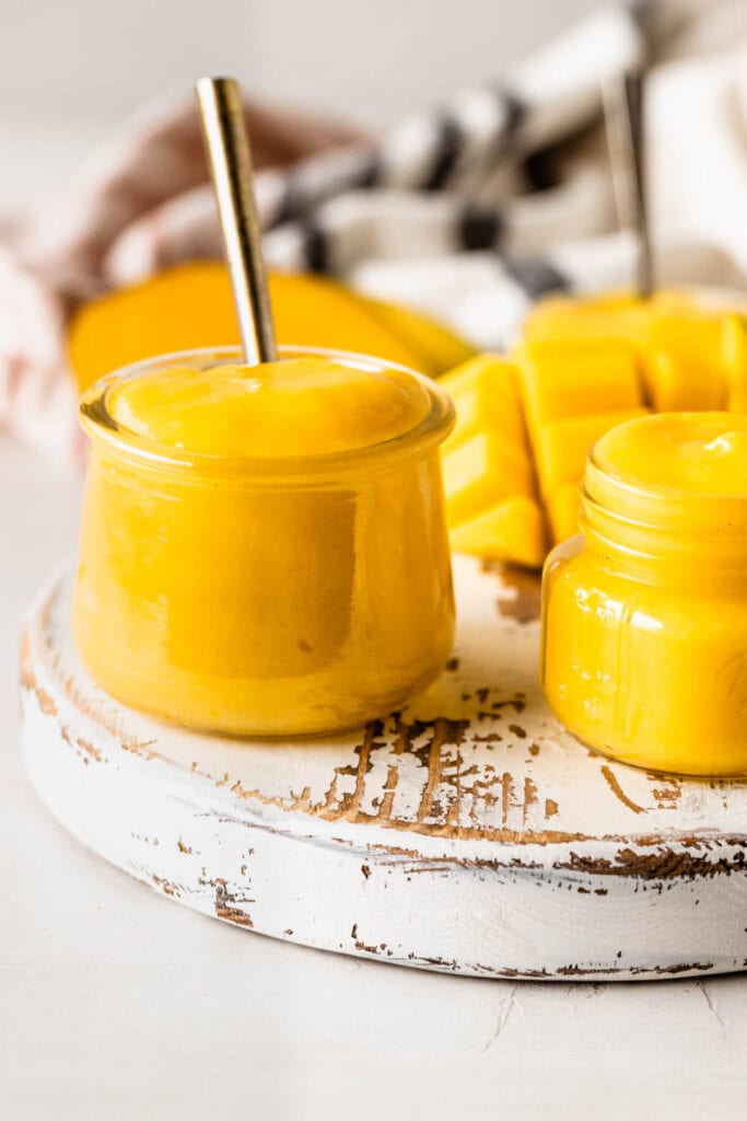 mango curd in a container with a spoon.
